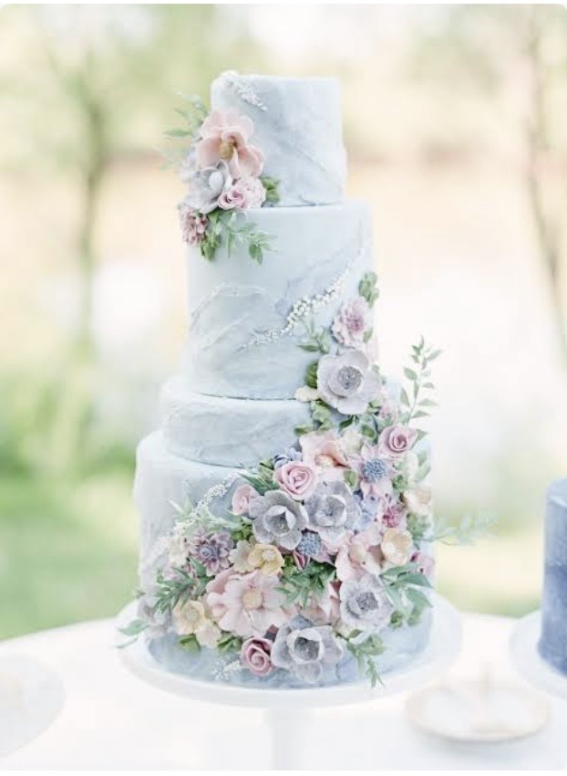A three-tier buttercream cake adorned with rosettes, berries and gold leaf